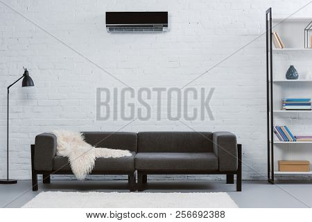 Modern Air Conditioner Hanging On White Brick Wall At Living Room