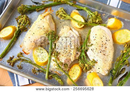 Overhead View Of Seasoned Chicken Breasts, Broccolini And Squash On A Sheet Pan