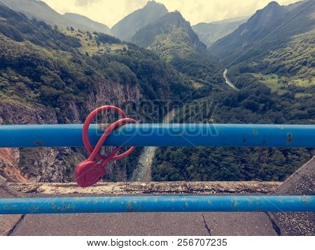 Red Lovelock Chained To A Metal Fence On A Bridge.