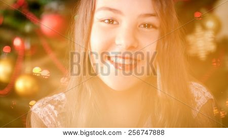 Portrait Of Beautful Smiling Girl Posing Against Decroated Christmas Tree