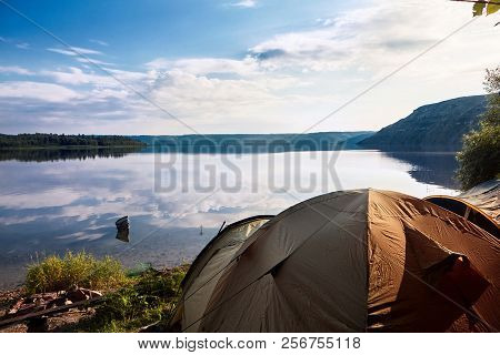Landscape Of River With Camping Tent On First Plan And River Reflection Of Clouds Over Wide Angle.re