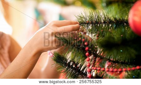 Closeup Image Of Young Girl Hanging Baubles On Christmas Tree Branches