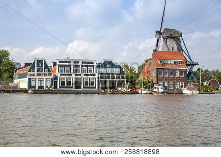 Traditional, Authentic Dutch Windmill And Houses At The River Zaam.