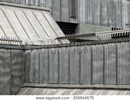 Anti Climb Security Rollers With Barbed Spikes On The Walls And Roof Of A High Security Building Wit