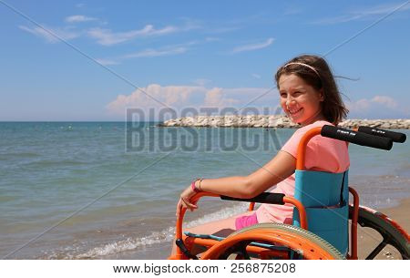 Smiling Little Girl On The Wheelchair On Summer By The Sea