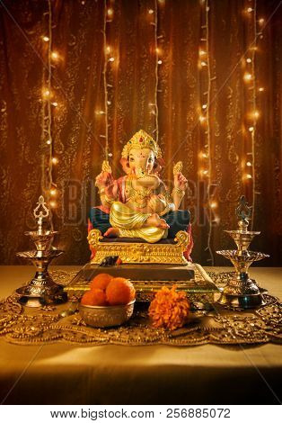 Beautiful handmade statue of Ganesha. Ganapati Festival set up and decoration with traditional lamps, prasad and lighting. âGaneshostavâ is celebrated in almost every home in Maharashtra, India.