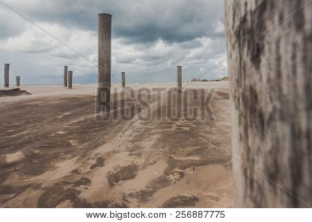Long Shutter Photo Of Wooden On Sandy Beach With White Clouds And Waves Of The North Sea