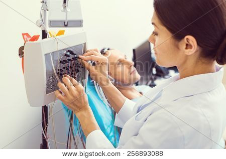 Female Lab Worker Setting Up Electroencephalography Machine