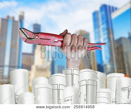 Hand Holding Pilers With Architect Plans And City Background