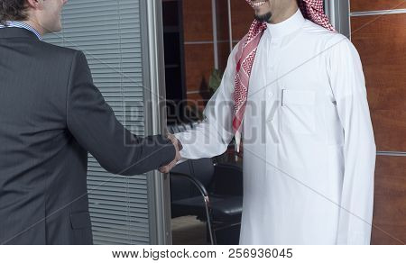 Middle Eastern And Caucasian Businessmen Shaking Hands, In An Office