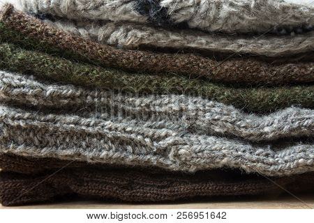 Stack Of Handmade Warm Knitted Socks Scarfs Mittens From Rough Wool Yarn Brown Beige Grey. Close Up.