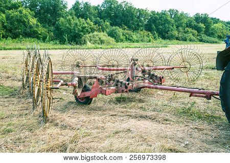 Tedders For Hay In The Meadow In The Background Of The Forest