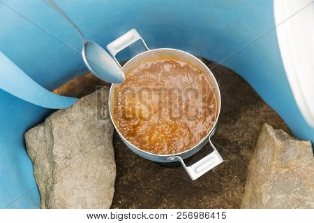 Process Of Making Soups In Marching Conditions On A Gas Burner Protected From The Wind By A Blue Kar