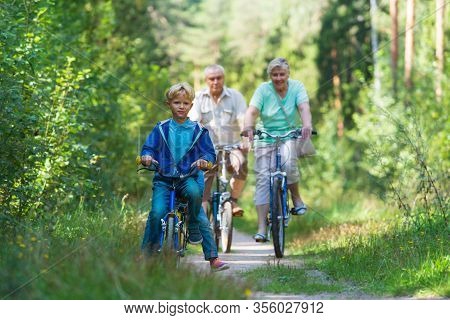 Active Senior Couple With Kids Riding Bikes In Nature
