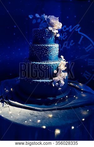Dark Blue Multi-tiered Wedding Cake Decorated With Sugar Beads And Flowers In The Dark