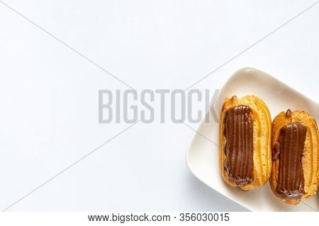 Part Custard Cakes With Chocolate Icing On A White Background. Copy Space