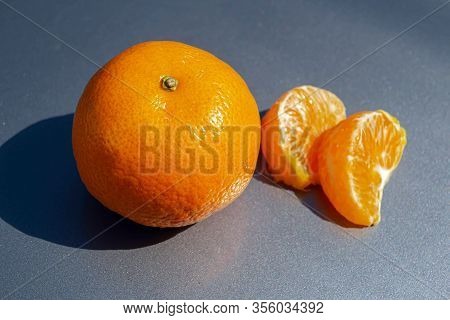 Whole Tangerine With Slices On A Gray Background