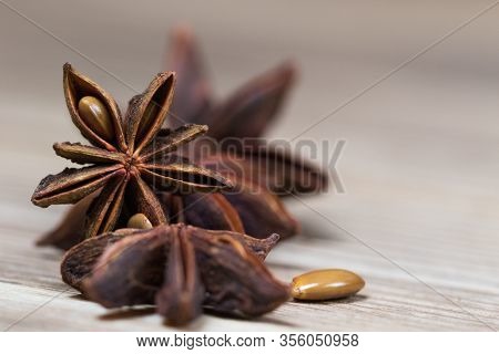 Star Anise With And Without Seeds, Closed, On A Light Wooden Surface. Spice For The Recipe. Beautifu