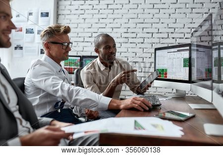 Successful Businessmen Trading Stocks. Stock Traders Looking At Graphs, Indexes And Numbers On Multi