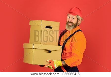 Man Wearing Boilersuit Packing Boxes. Move To New Apartment. Bearded Loader In Uniform. Cardboard Bo