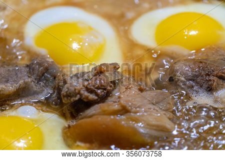 Fried Eggs And Pieces Of Meat In A Frying Pan In Sunflower Oil Close-up. Concept Of Homemade Food