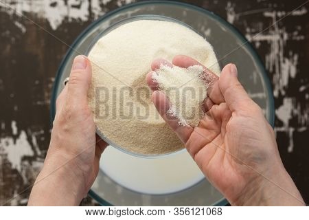 Top View Of Womah Hand Putting Semolina Into Bowl With Milk As Ingredient For Baking Mannik Casserol
