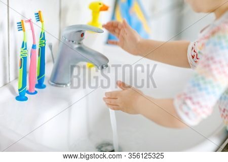 Closeup Of Little Toddler Girl Washing Hands With Soap And Water In Bathroom. Close Up Child Learnin