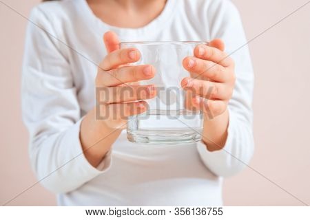 Cute Cild Holding Glass Of Water At Neutral Background. Water Balance Concept. Close Up Glass Of Wat