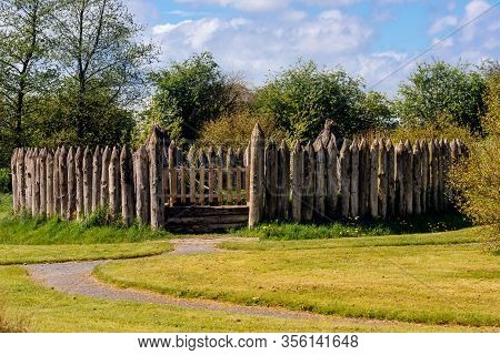 Old Wooden Palisade Of The Fort Or Camp Surrounded By Green Fields And Trees. Depicting Early Age Of
