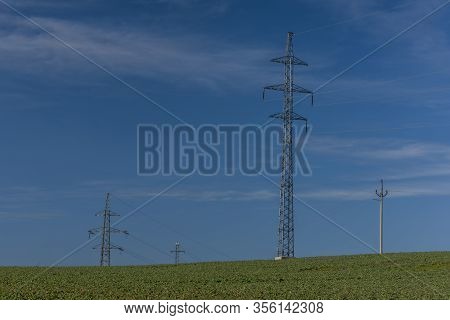 Hight Electric Wires And Poles On Green Spring Field With Blue Sky