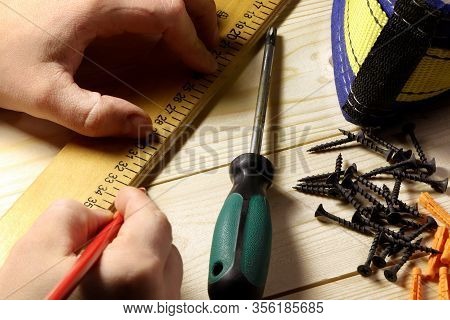 Different Tools On A Wooden Background. Carpenter Tools On A Table. Hand Holding Riler And Pencil.