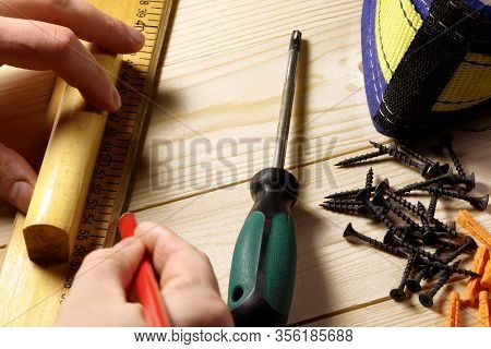 Different Tools On A Wooden Background. Carpenter Tools On A Table. Hand Holding Riler And Pencil.