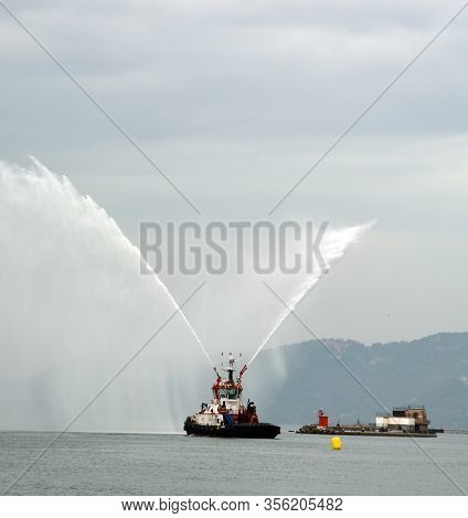 Trieste Italy 05 19 2019: Deneb Tug Boat In Trieste Italy Giving Farewell Salute With Fire Hoses Wit