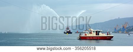 Trieste Italy 05 19 2019: Deneb Tug Boat In Trieste Italy Giving Farewell Salute With Fire Hoses Wit