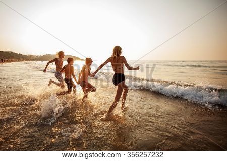 Smiling teens run on vacation. Happy young peaple having fun at beach on sunny day.