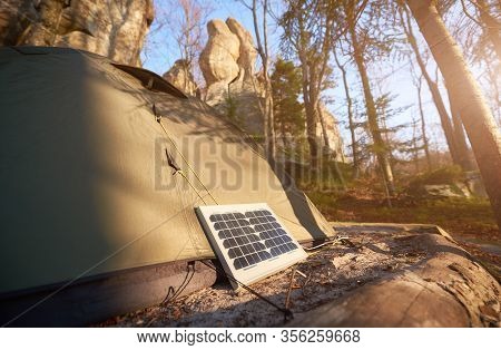 Tourist Solar Panel And Tent In The Forest At The Foot Of The Cliffs. Fir Trees And Fallen Leaves On