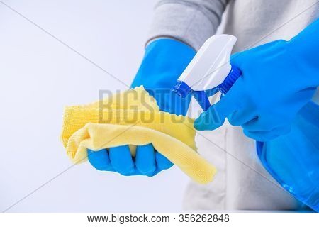Young Woman Housekeeper In Apron Is Cleaning, Wiping Down Table Surface With Blue Gloves, Wet Yellow