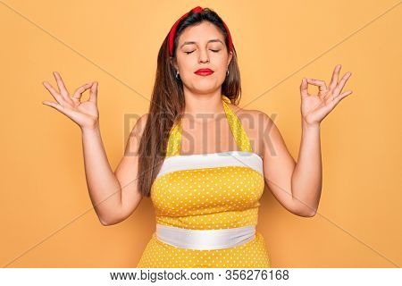 Young hispanic pin up woman wearing fashion sexy 50s style over yellow background relaxed and smiling with eyes closed doing meditation gesture with fingers. Yoga concept.