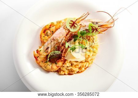 Risotto tom yam with argentinian shrimp. Delicious thai dish with seafood closeup view. Traditional asian meal with rice and aromatic greenery. Food composition on white plate. Restaurant delicacy