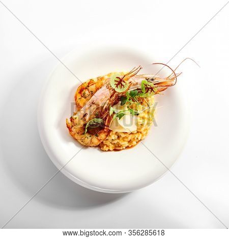 Risotto tom yam with argentinian shrimp. Delicious thai dish with seafood closeup view. Traditional asian meal with rice and aromatic greenery. Food composition on white plate. Restaurant delicacy