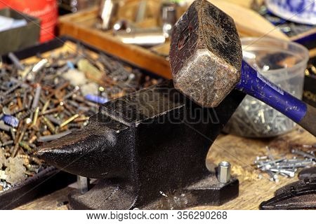 An Anvil And Sledgehammer On A Wooden Table.a Stithy.