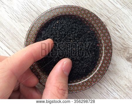 Close Up Of Nigella Seeds / Black Cumin / Black Onion Seed/ Black Sesame Seed With Male Hand. Tradit