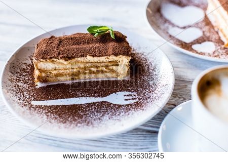 Tiramisu Cake On A Table With A Cup Of Coffee