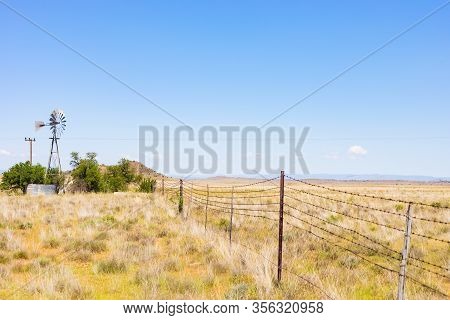Windmill On A Farm In Rural Grassland Area Of South Africa