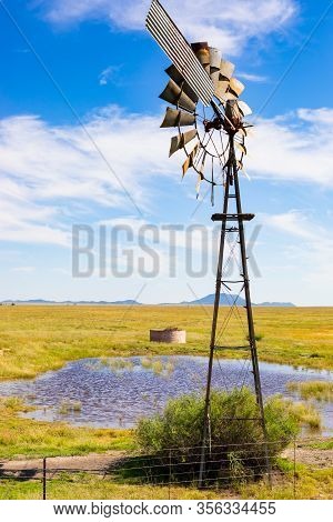 Windmill On A Farm In Rural Grassland Area Of South Africa