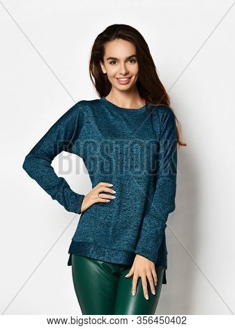 Smiling Young Pretty Brunette Woman In Casual Blue Sweatshirt Jersey And Grey Leather Jeggings Is Po