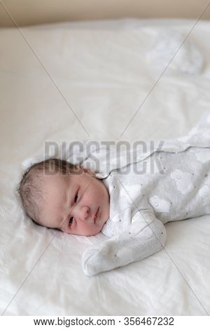A Newborn Baby Lies On Its Back With Open Eyes In The First Minutes Of Life. A Newborn With Traces O