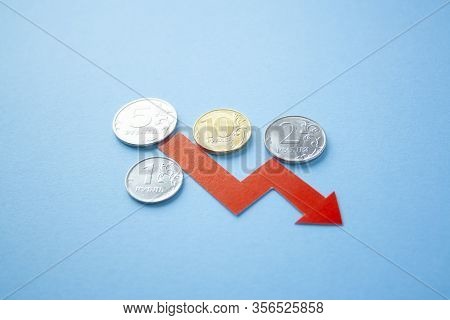 Many Rouble Coins On Blue Background With Red Arrow Down. Exchange Rate Chart. Ruble Depreciation. E