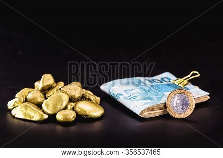 Currency And Money Notes From Brazil Next To Pile Of Gold Nuggets. Wealth Or Luxury Concept.