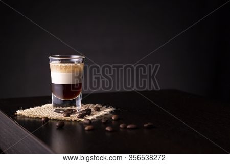 B-52 Layered Cocktail Shot On A Burlap Coaster Decorated With Fresh Roasted Coffee Beans Placed On A